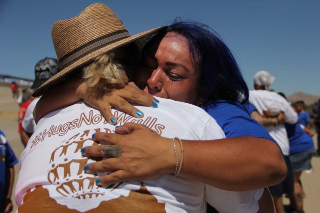 Mexican families living in US and Mexico embrace at the border line in the bank of Rio Grande to take part in the event called "Abrazos No Muros" (Hugs, not walls) promoted by the Border Network of Human Rights organization in the border line between El Paso, Texas, United States and Ciudad Juarez, Chihuahua state, Mexico on May 12, 2018. / AFP PHOTO / HERIKA MARTINEZ