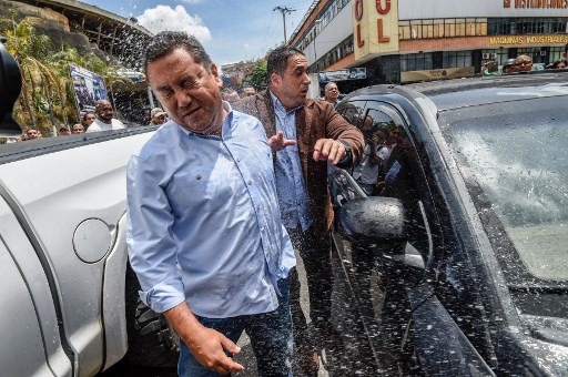 Venezuelan opposition presidential candidate and evangelical pastor Javier Bertucci (L) is thrown water by relatives of prisoners who didn't want candidates doing politics at El Helicoide, the headquarters of the Bolivarian National Intelligence Service (SEBIN), in Caracas, on May 17, 2018, where Venezuelan opponents and a US citizen have seized control of the detention centre. The Venezuelan opponents and a US Mormon missionary, who took control of the cell block area on the eve, are demanding the release of prisoners, according to videos broadcast on social networks. / AFP PHOTO / Juan BARRETO