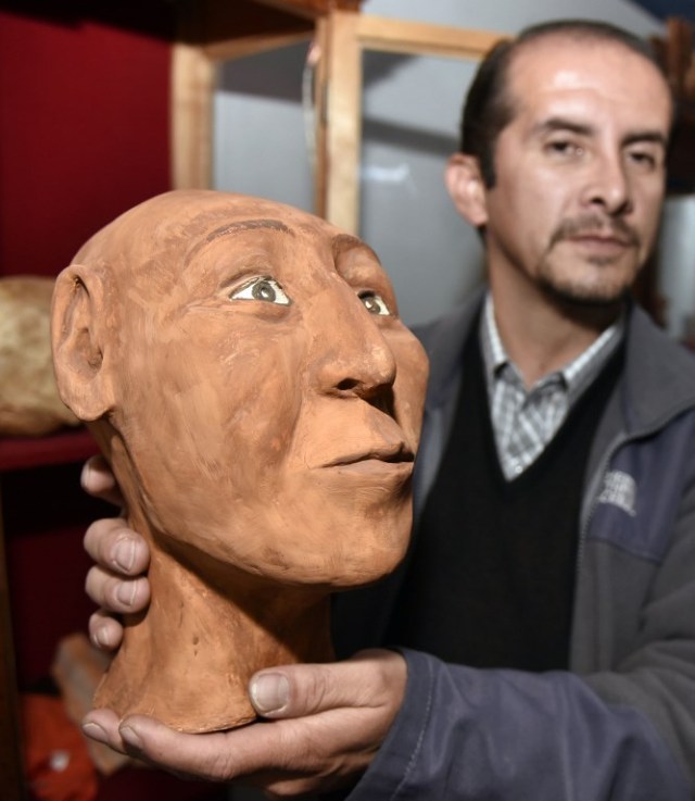 Forensic Anthropologist Luis Castedo shows one of the three facial reconstructions of human skulls from the Tiwanacu culture, he has been working on, in La Paz on May 18, 2018.   The 1,100-year-old skulls were found at the Kalasasaya temple in the archaeological site of Tiwanakuque. Castedo says he will reconstruct 10 more skulls for the end of the year.  / AFP PHOTO / AIZAR RALDES