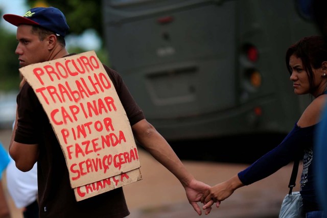A Venezuelan migrant uses a sign to apply for a job near a makeshift camp at Simon Bolivar square in Boa Vista, Brazil May 3, 2018. Picture taken May 3, 2018. The placard reads "Looking for work, carpentry, painting, farming and general services." REUTERS/Ueslei Marcelino