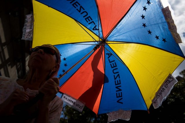Una persona abre una sombrilla con los colores de la bandera venezolana durante una de las manifestaciones en contra de las elecciones presidenciales hoy, sábado 17 de marzo de 2018, en Caracas (Venezuela) EFE/Miguel Gutiérrez 